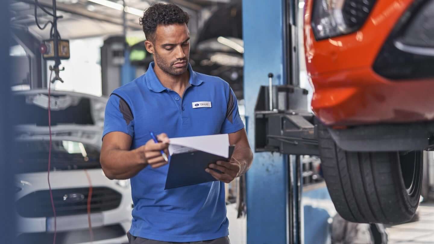 Homme inspecte véhicule rouge